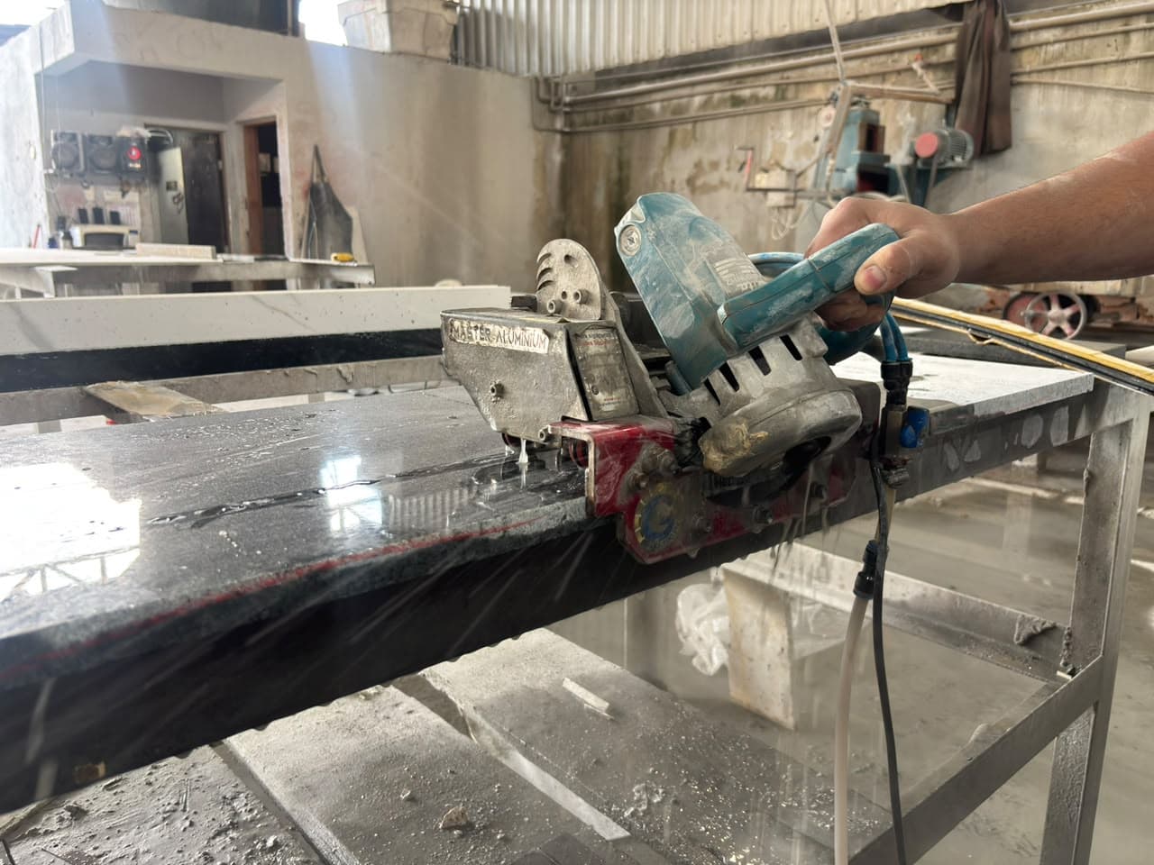 Bancada de granito escuro sendo cortada com serra refrigerada a água