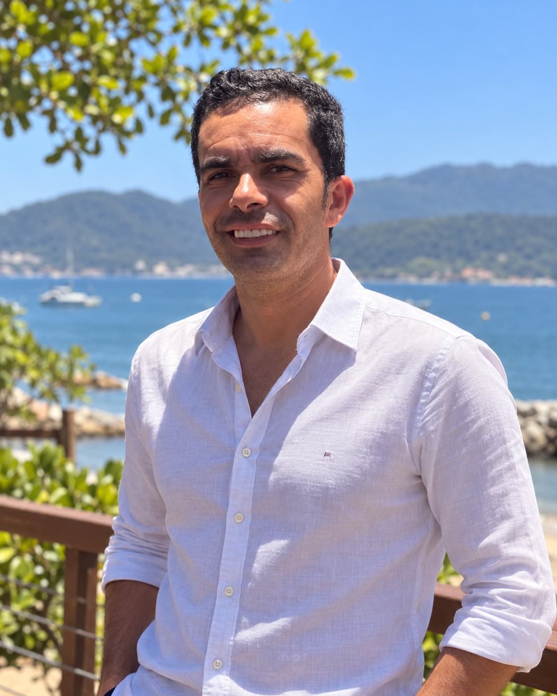 Retrato de Rafael (Kaka) Cipola, de camisa branca, com o mar e as montanhas ao fundo