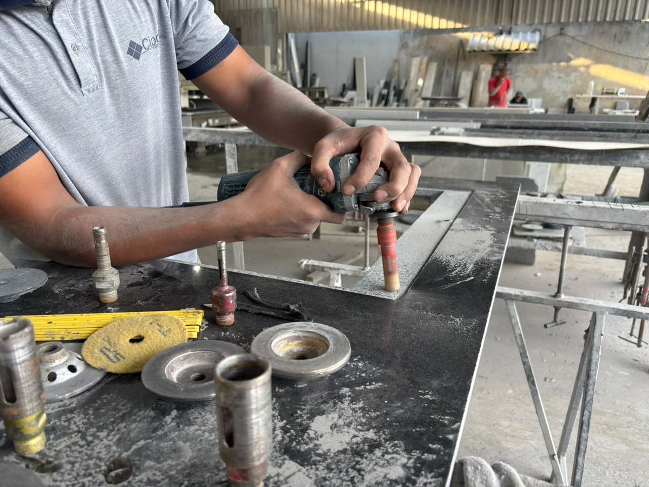 Profissional da Cipola abrindo o recorte da cuba em uma bancada escura, com brocas e discos de polimento sobre a pedra